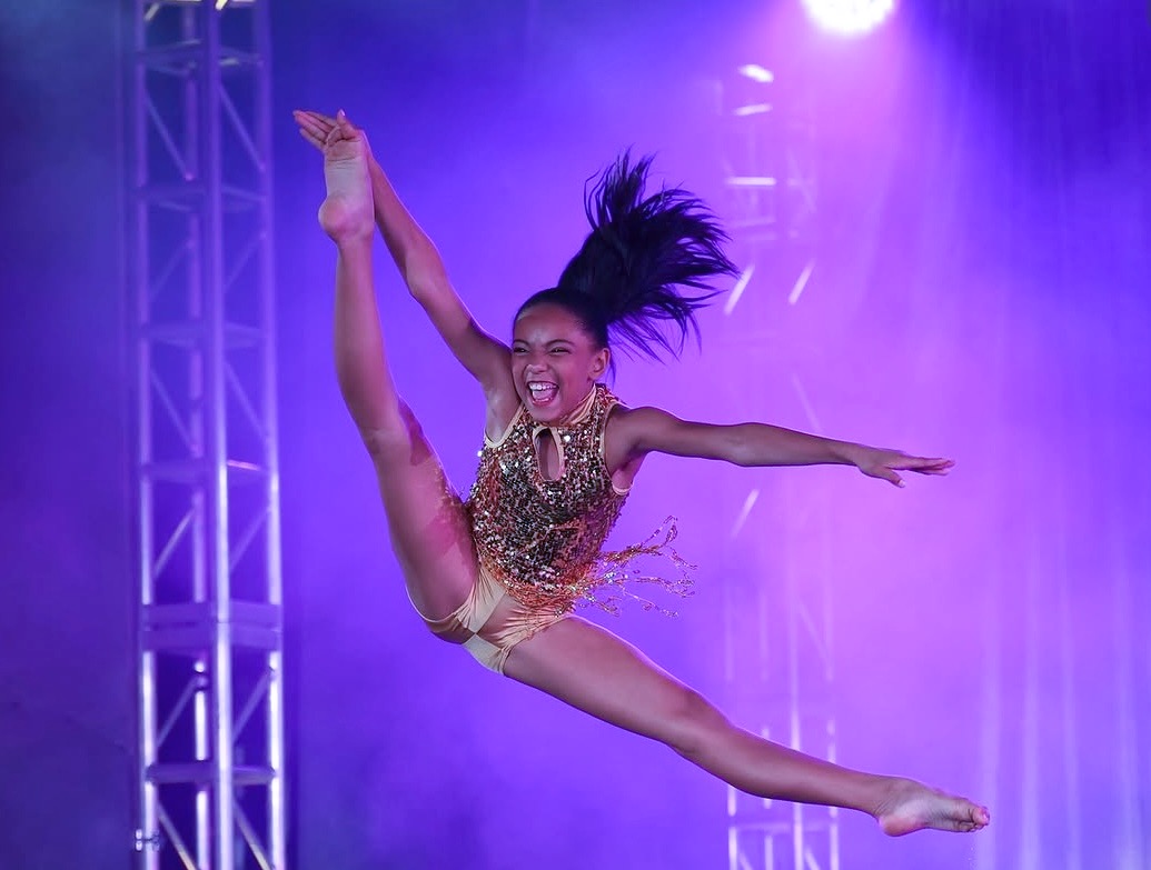 Moonstar competition dancer mid-leap on stage